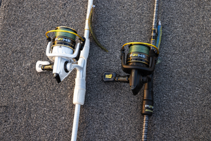 Two Abu Garcia + PRIME21 Collaboration Spinning Combos laying flat on pavement, one black & one white. 