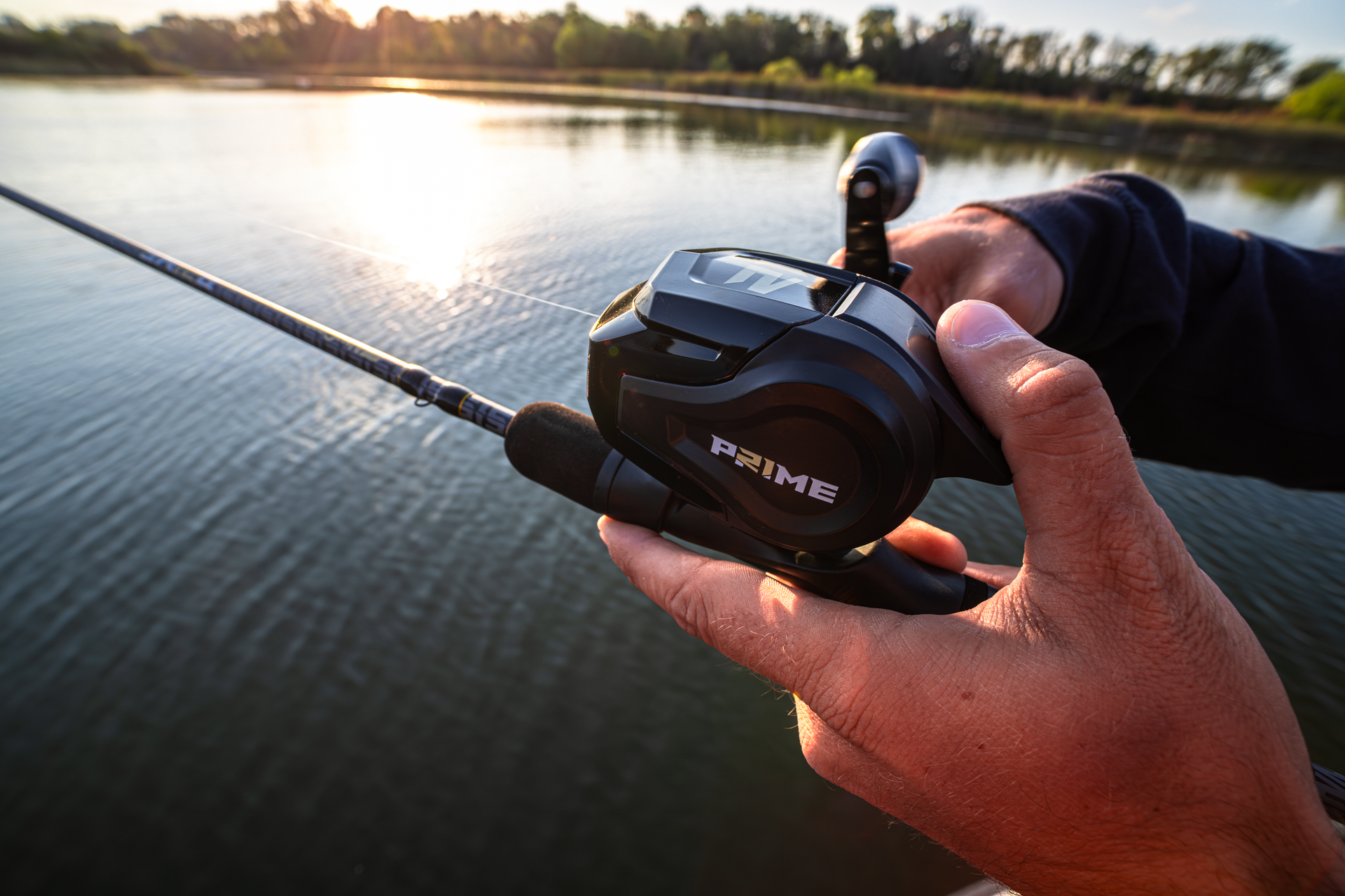 Hand holding a the Abu Garcia + PRIME21 Spincast Combo over a body of water.