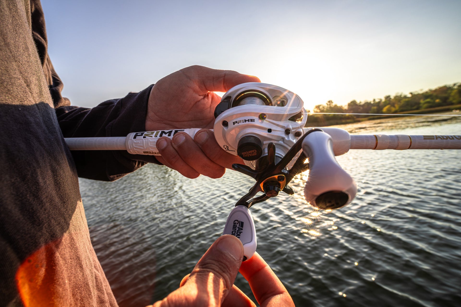 Close up of a Abu Garcia x PRIME21 Low Profile Baitcast Combo in man's hand over the water.