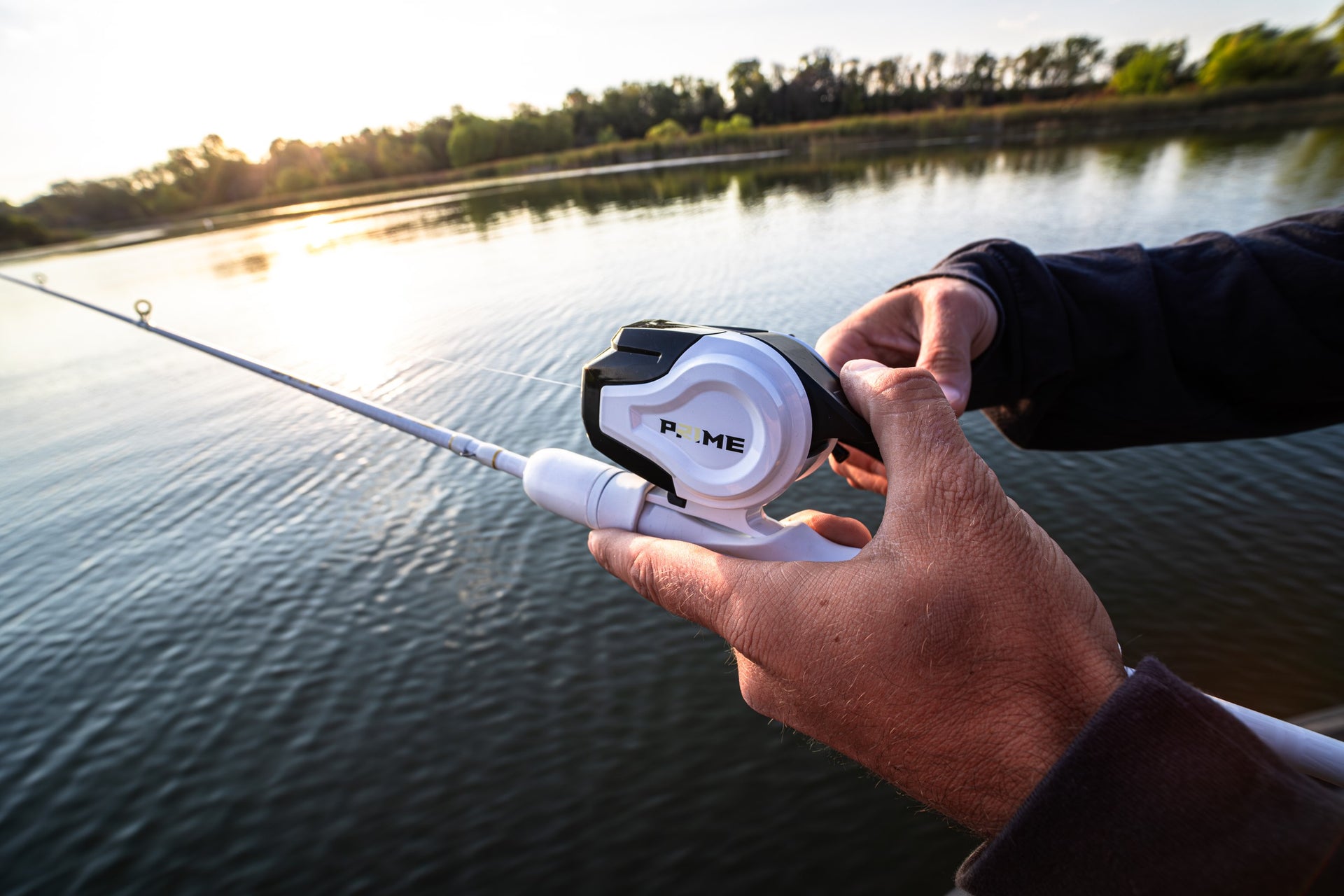 Close up of a Abu Garcia x PRIME21 Spincast Combo in a man's hand over the water 