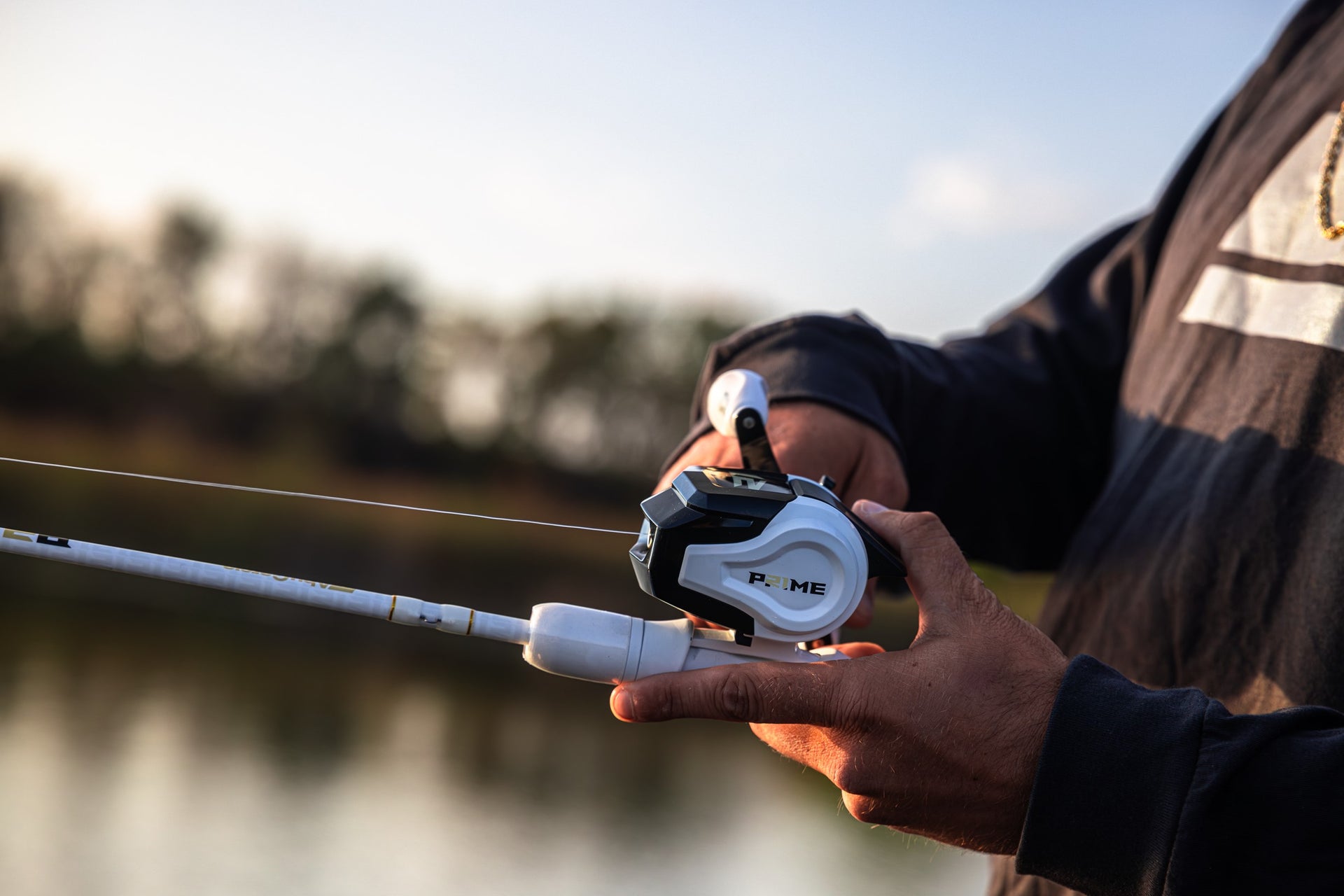 Close up of a Abu Garcia x PRIME21 Spincast Combo in a man's hand over the water 