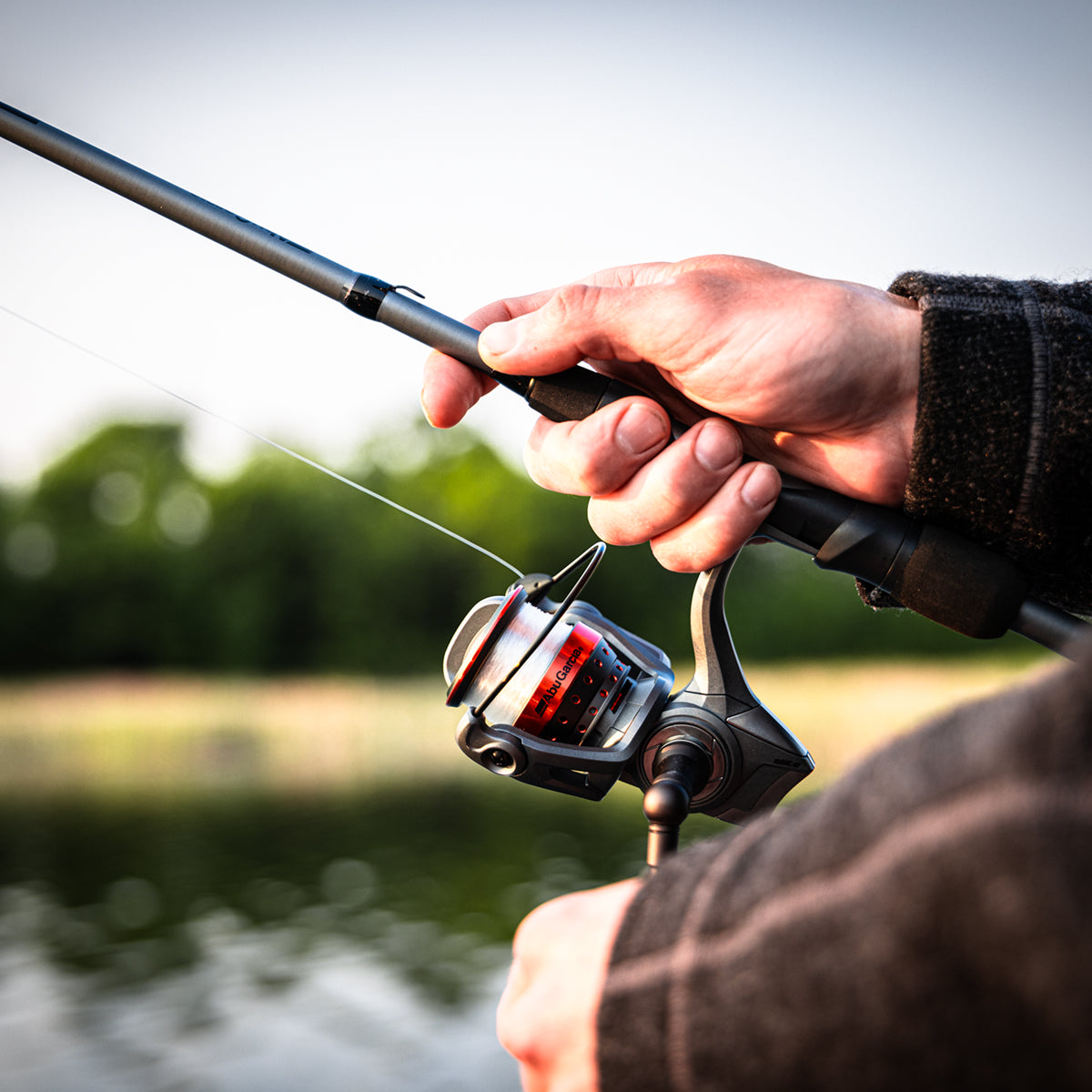 Hand holding an Abu Garcia Fishing Combo with a blurred background. 