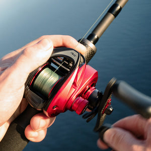 Abu Garcia Revo® Rocket Low Profile Reel in a hand over a blurred blue background.