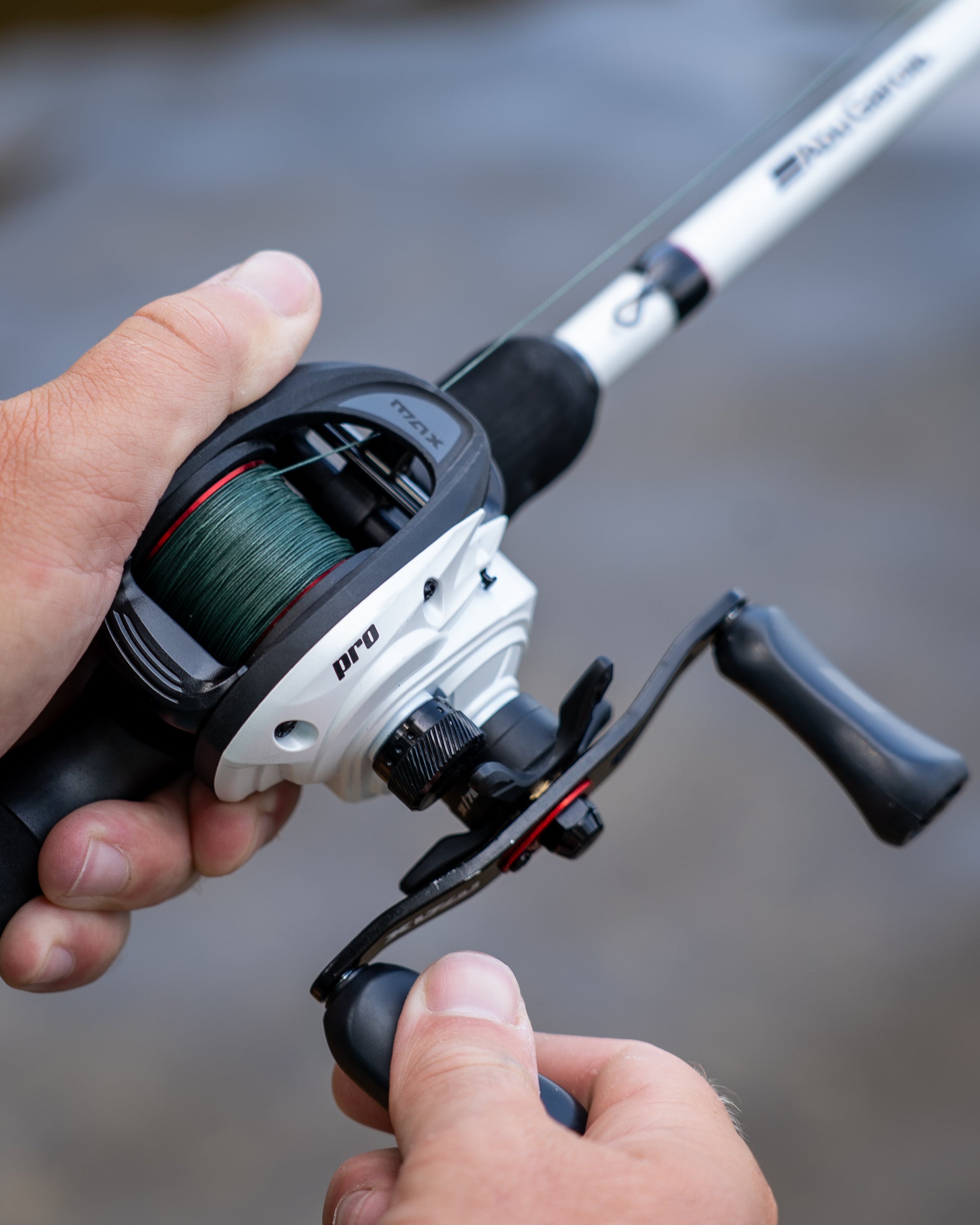 Close up of an Abu Garcia Max Pro Fishing reel held by a person with a blurred natural background