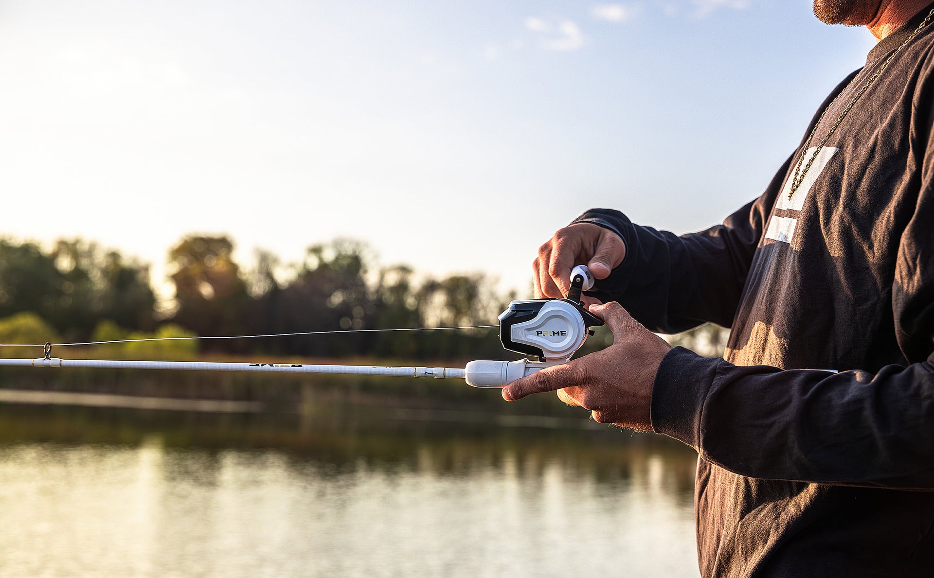 Person fishing by a lake with a sunset in the background