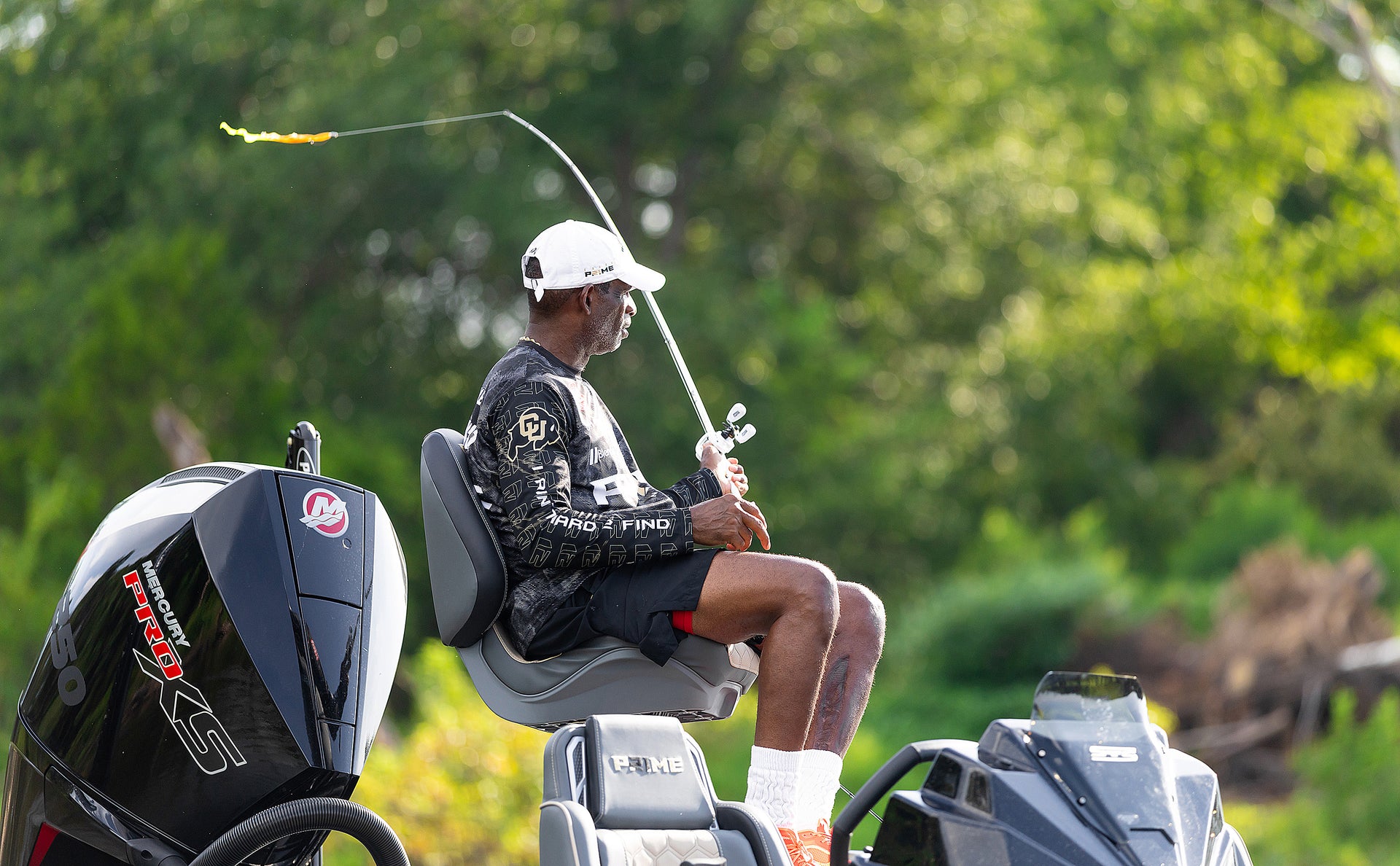 Man fishing from a boat with a blurred green background