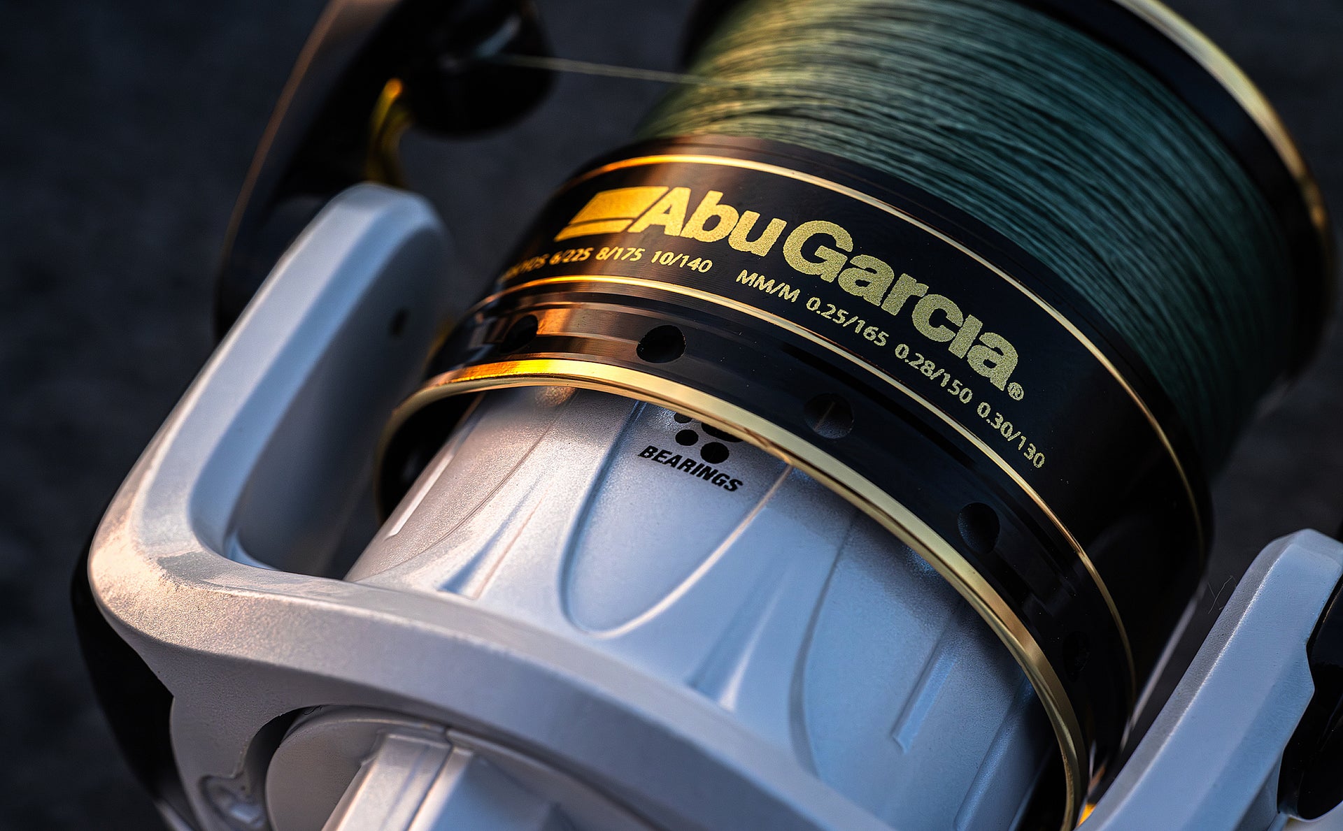 Close-up of Abu Garcia fishing reel with green line on a dark background