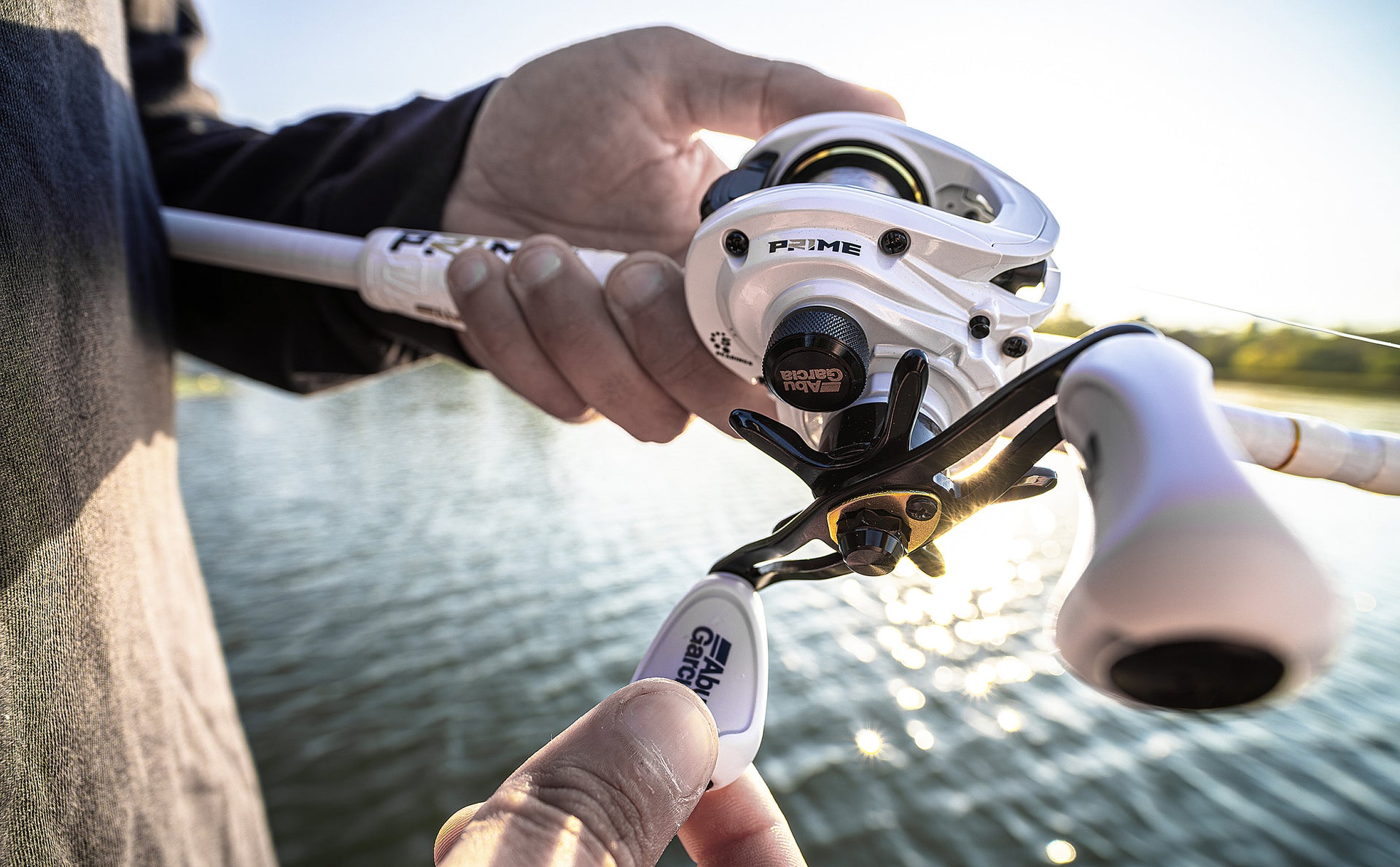 Fishing reel held by a person with water and sky in the background
