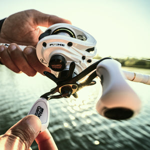 Fishing reel held by a person with a blurred lake background