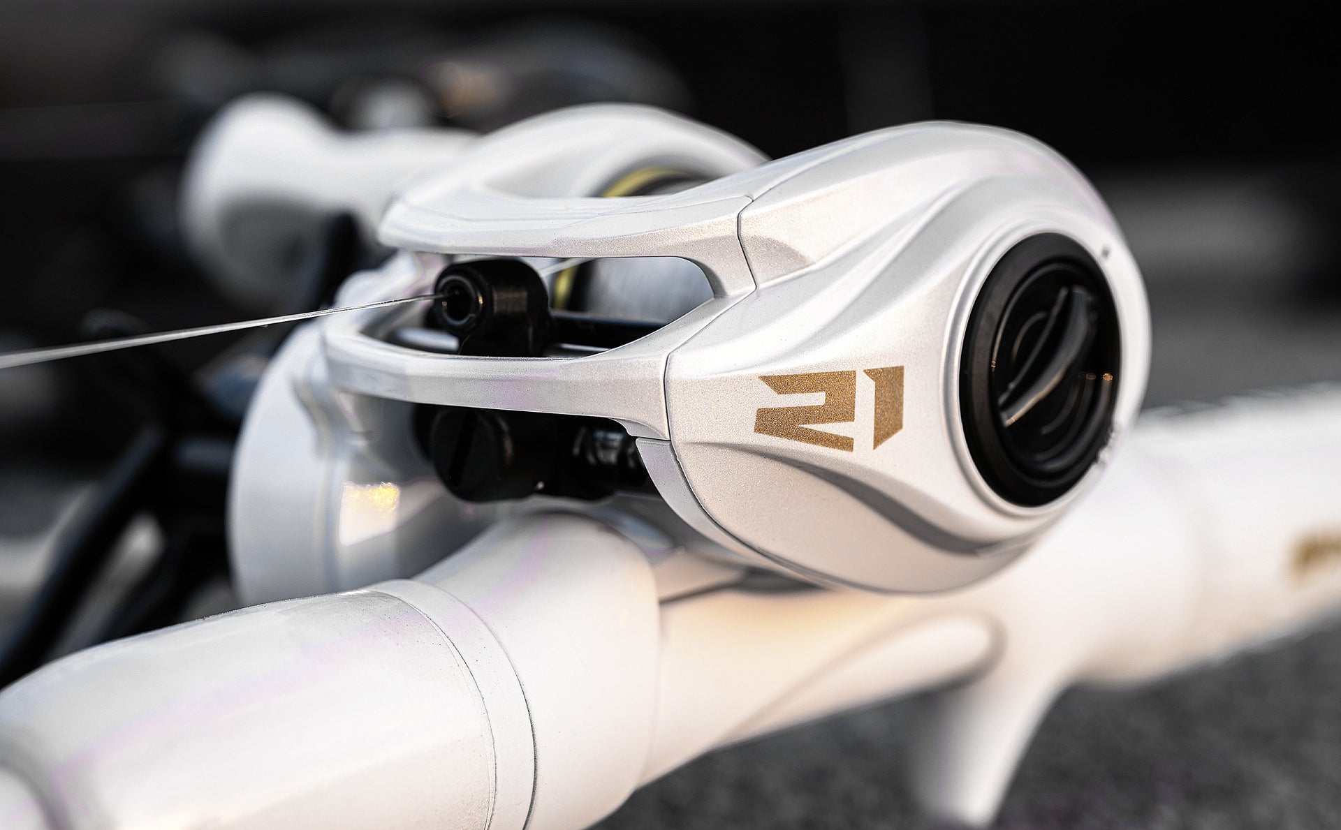 Close-up of a fishing reel with '21' branding on a blurred background