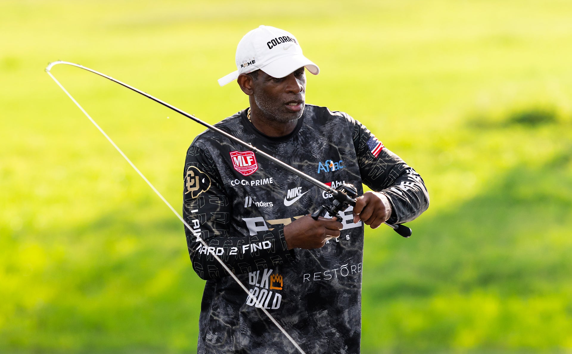 Man holding a fishing rod on a grassy field