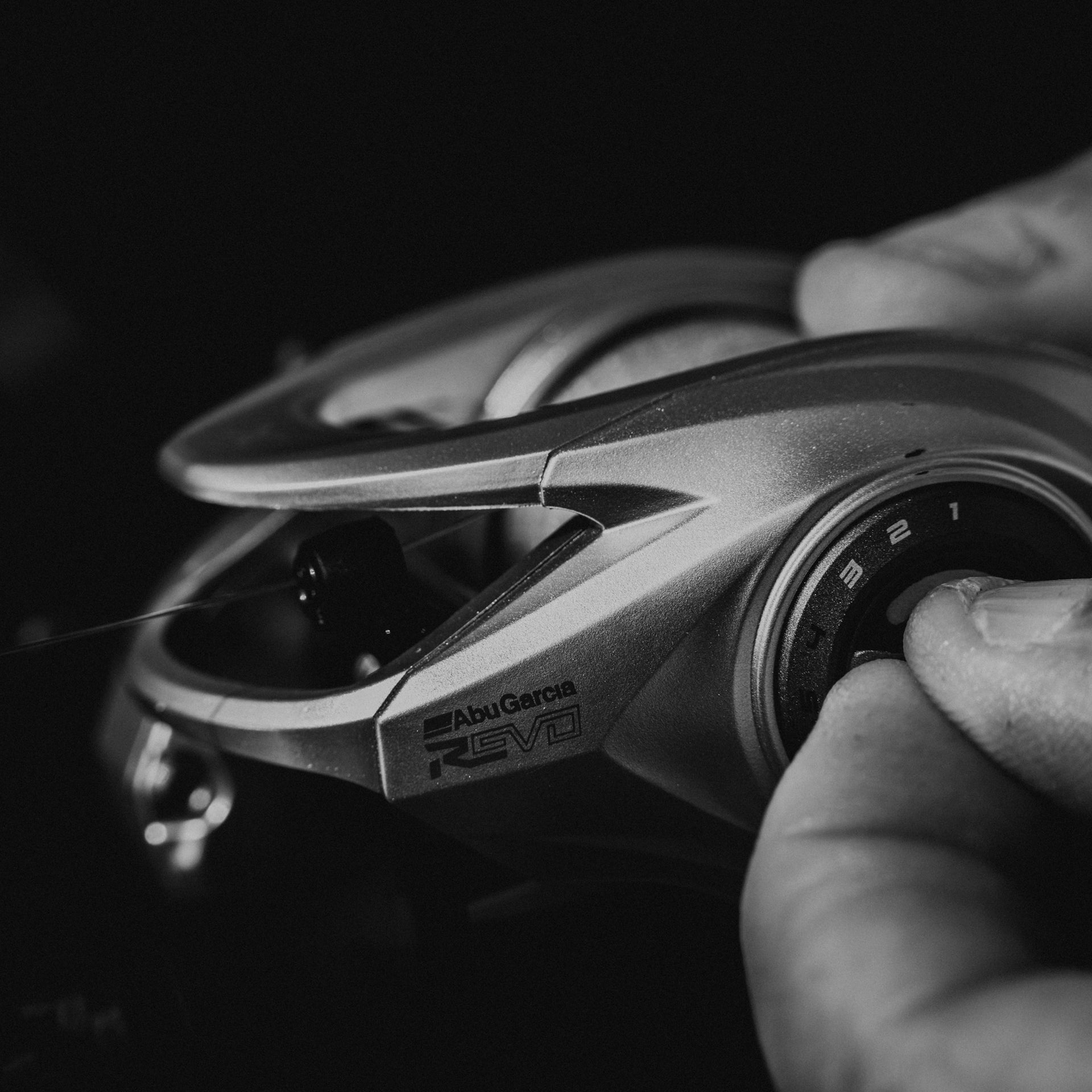 Close-up of a Abu Garcia reel with a hand adjusting the spool.