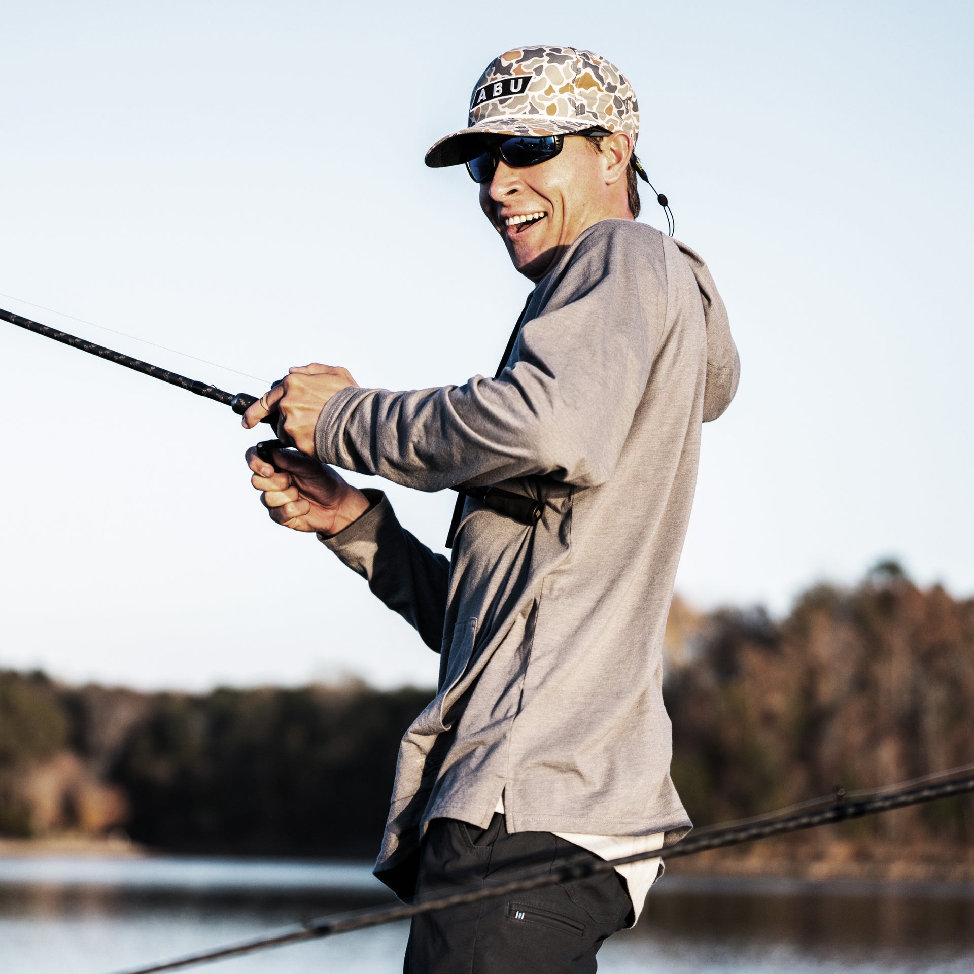 Man fishing by a lake with trees in the background