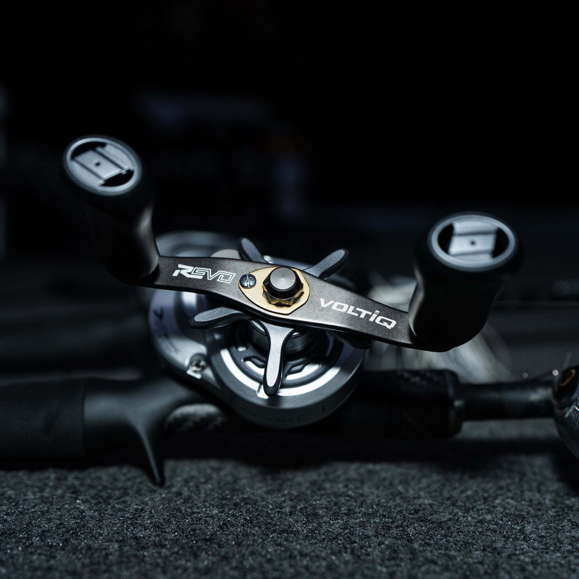 Close-up of a motorcycle handlebar with 'Revo' and 'Voltiq' branding on a dark background.