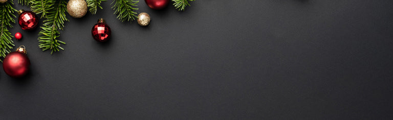 Christmas decorations including red and gold ornaments and green pine branches on a dark background.