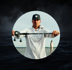 Man holding a Beast fishing rod with a fish on a dark water background